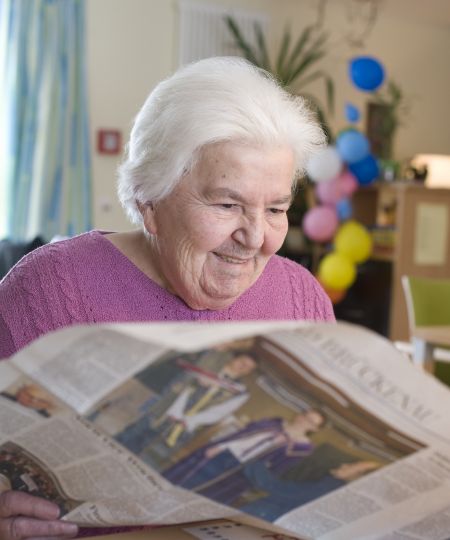 alte Dame beim Zeitung lesen